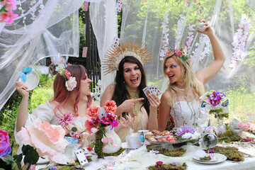 Drei als Elfen oder Feen verkleidete Frauen streiten sich um ein Kartenspiel