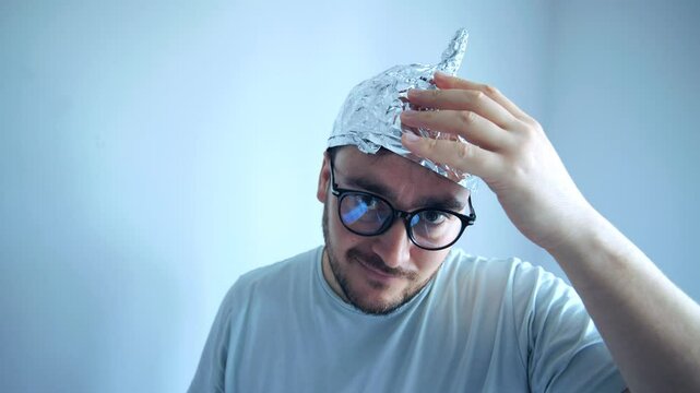Man wearing a tinfoil hat shows disbelief and humor while expressing paranoia and fear of conspiracy theories