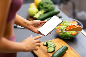 Woman Using Smartphone Cooking Searching Vegetable Salad Recipes Preparing Healthy Dinner For Weight Loss Standing In Kitchen At Home. Female Nutrition, Detox Diet Concept. Cropped, Mockup
