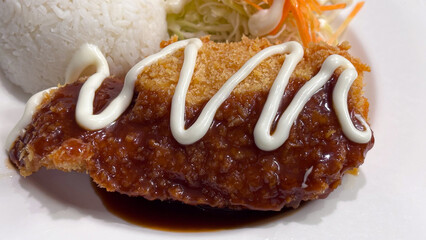 Close-up of Chicken Katsu with rice and salad, drizzled with sauce and mayonnaise