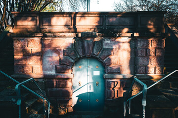 Historic arched doorway built into a red sandstone wall, framed by two staircases leading up on...