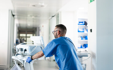 Obraz premium Doctor pushing medical equipment in hospital corridor