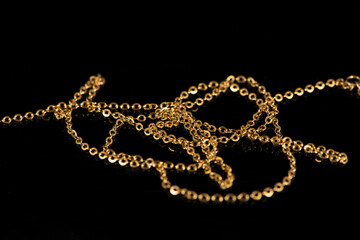 closeup of gold jewelry chains set on black background. 