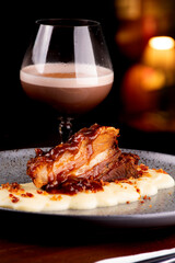 dish of pancetta under parmesan cream harmonizing with chocolate cocktail and blurred background