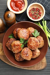 Delicious patties and spices on black textured table, flat lay