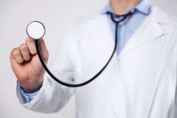 Doctor with stethoscope on light background, closeup