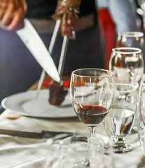 Blurred Waiter cutting grilled meat with a knife and fork in a restaurant