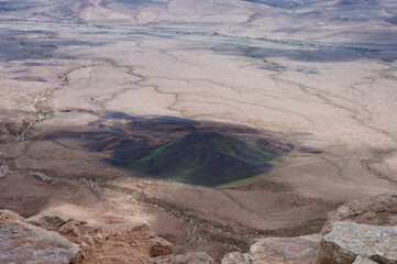 A desert landscape with a large green hill in the middle