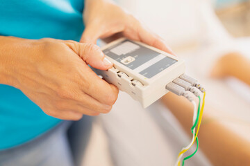 A physiotherapist applies electrostimulation therapy to a patient's muscles, using TENS unit, (transcutaneous electrical nerve stimulation), and electrodes,