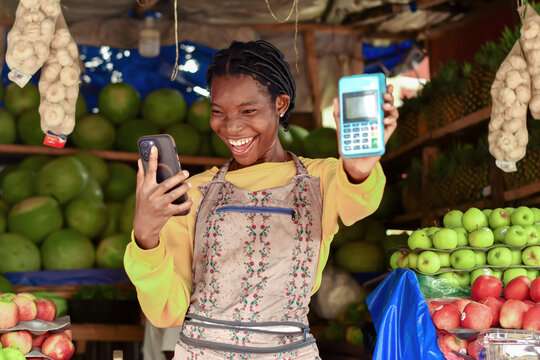 happy fruit salesperson holding up mobile payment terminal
