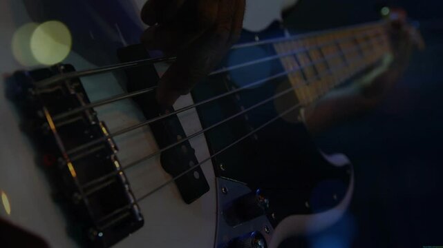 Musician plucking bass guitar strings under stage lights, with animated music waveform bars pulsing