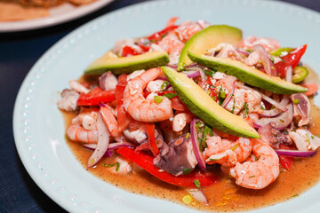 Seafood salad with shrimps, octopus, avocado, tomatoes and onions on light blue plate