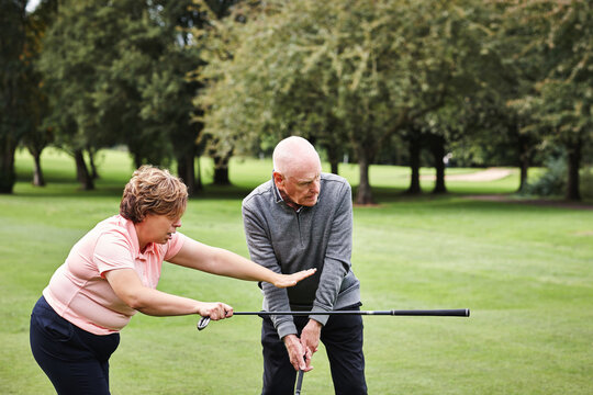 Golf course, instructor and senior man learning at club, field or outdoor in nature to help with lesson. Golfers, coach and teaching elderly person, exercise or training together for sports in summer - Powered by Adobe