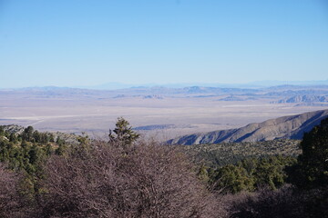 A sweeping view of the California desert basin unfolds from the mountains near Big Bear, framed by ridges and distant blue peaks under a crystal-clear sky.