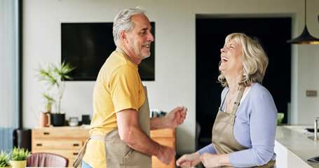 Obraz premium Senior, couple and dancing in living room or happy with bonding, retirement and marriage in apartment. Elderly, man or woman with energy for laughing, apron and romance with smile in house or home