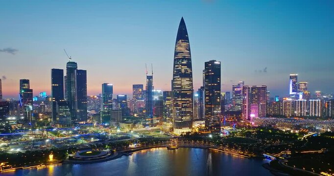 Aerial shot of illuminated modern city skyline with skyscraper reflecting on the water at night in Shenzhen, China.