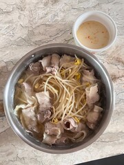 A steaming pot of shabu-shabu with thinly sliced meat, fresh vegetables, and dipping sauces. This...