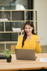 Asian woman sitting and working on laptop in office