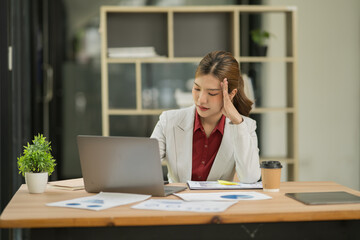 Obraz premium Asian businesswoman sitting using laptop, working with a stressed expression on her face.
