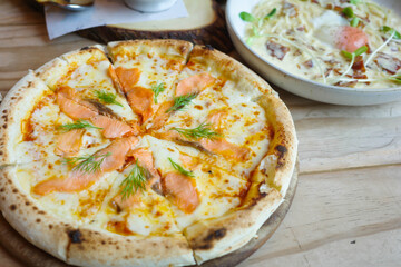 Delicious hot pizza with smoked salmon, on wooden table ready to eat. Smoked salmon pizza with salmon and mozzarella. Smoked salmon pizza front 