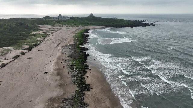 Aerial view of a sandbar and coastal shoreline along Taiwan&rsquo;s northeast coast, with waves surrounding the sand formation.