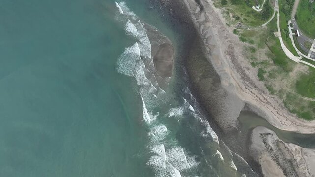 Aerial view of a sandbar and coastal shoreline along Taiwan&rsquo;s northeast coast, with waves surrounding the sand formation.