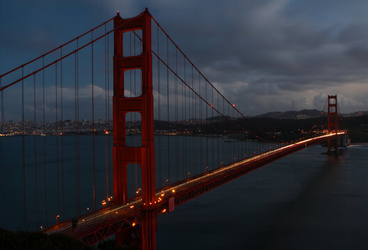 Golden Gate Bridge illuminated at night with city lights twinkling in the distance, highlighting iconic architecture and travel landmarks in San Francisco. - Powered by Adobe