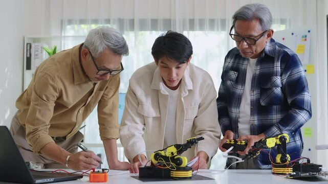 asian Robot arm engineers brainstorming in workshop to develop control technology with teamwork and coding innovation