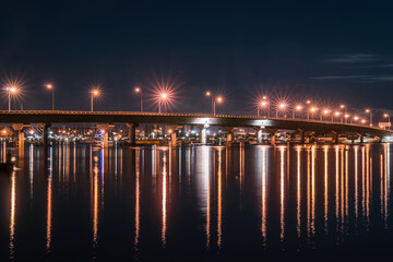 Tauranga harbour bridge curves across bay illuminated at night worth star-bursts from street lights.