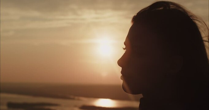 Young woman watching golden sunset over river