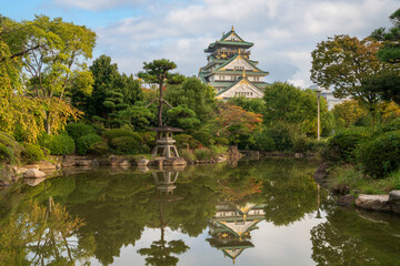 Osaka Castle with reflection in a pond in a Japanese garden on the castle grounds on a sunny autumn morning, Osaka, Japan