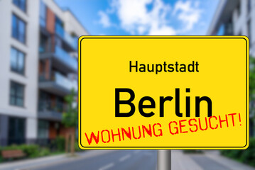Eine Stra&szlig;e mit modernen Mehrfamilienh&auml;usern und Schild Berlin Wohnung Gesucht