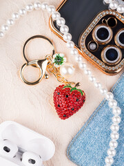 Close up of metallic gold keychain with rhinestones in the shape of strawberry with leaves on the...