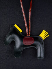 Close up cute leather black horse keychain with saddle for bag on black background