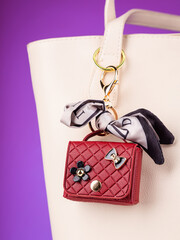 Close up cute leather keychain earphone case red  handbag with decorative charms  on white bag