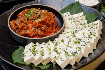 Sliced ​​tofu and spicy kimchi on a black plate
