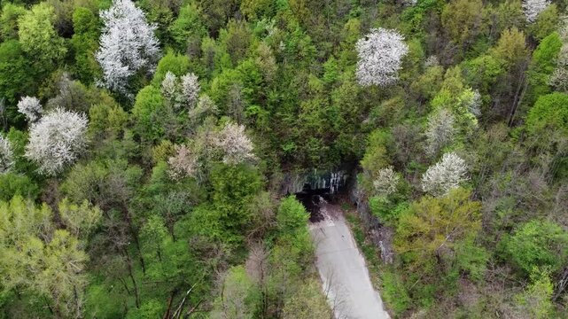 Left-orbit drone shot reveals airplane-shaped reinforced entrance of secret Željava Airbase in a Bosnian mountain, Klek 505, with a short runway vanishing into the tunnel.