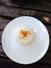 Plain white steamed rice served in a white plate on wooden table. rice with fried onion topping