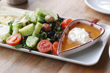 Fresh salad platter with olives, tomatoes, and honey dip is served