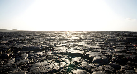 Obraz premium Textured Volcanic Rock Formations Against a Bright Sky at Sunset