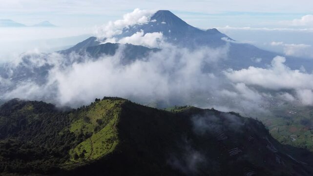 Aerial view of Mount Prau, Central Java, Indonesia, captured on April 28, 2025. Rolling green hills and misty peaks create a stunning natural landscape under the clear blue sky