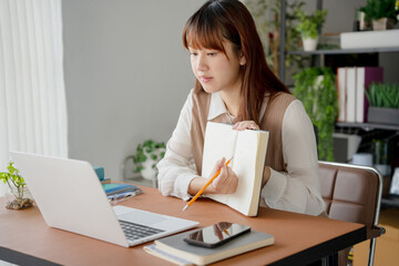 Asian woman using laptop to study student engaged in online learning at college