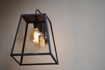 Elegant hanging lantern with warm light on plain wall