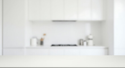 A softly blurred view of a bright, all-white kitchen with a clear countertop in the foreground, suggesting a clean and modern culinary space.