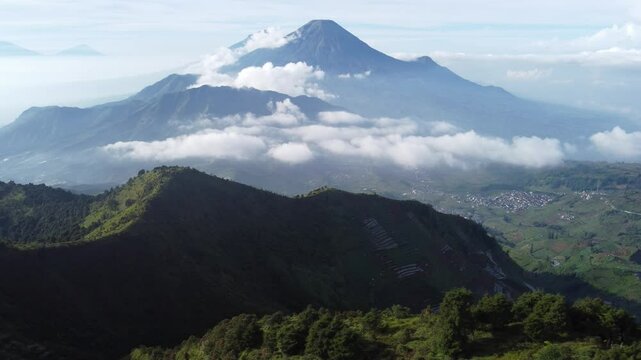 Aerial view of Mount Prau, Central Java, Indonesia, captured on April 28, 2025. Rolling green hills and misty peaks create a stunning natural landscape under the clear blue sky