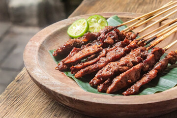 close up of chicken satay dish on a plate with banana leaves and peanut sauce.traditional Indonesian food.
