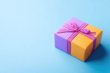single gift box wrapped in vibrant paper with ribbon on smooth solid background with ample copy space