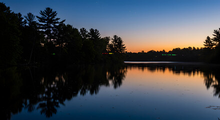 Obraz premium Quiet Twilight Scenery With Silhouetted Trees Reflecting On A Calm Lake