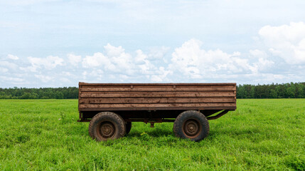 Obraz premium Abandoned wooden cart on green field under blue sky, evoking nostalgia and tranquility