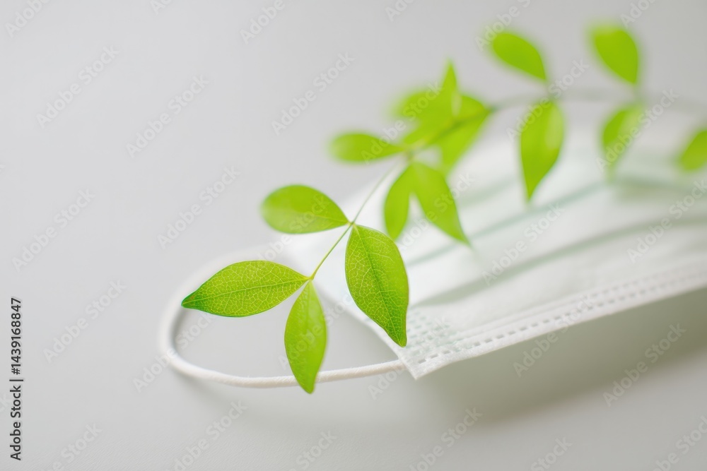 Aufkleber close-up of medical mask with leaves subtly intertwining through its fibers representing delicate co